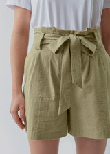 Panne shorts in the color Elm are made from a structured cotton quality. These shorts have a casual, high-waisted silhouette detailed with a belt at the waist. The model is 173 cm and wears a size S/36