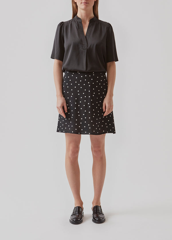 High-waisted mini skirt in black in a dotted EcoVero viscose with an airy fit. Covered elasticated waist on the back and a smooth back. The model is 173 cm and wears a size S/36
