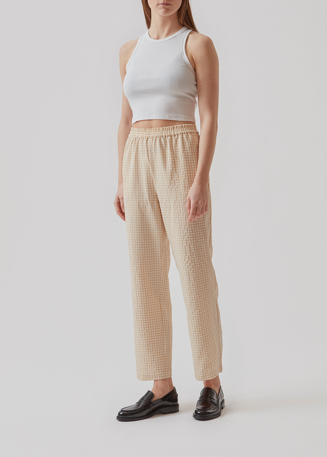Straight, wide pants in beige in check with elasticated waist, pockets at side, and a decorative fake back pocket. The length is slightly cropped. The model is 173 cm and wears a size S/36.