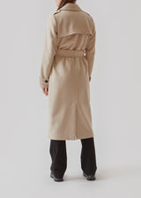 Classic, double-breasted wool coat in beige with collar and notch lapels. ShayMD coat has a wide tiebelt at waist, shoulder straps, wide cuffs and open yoke. With lining and single back vent.