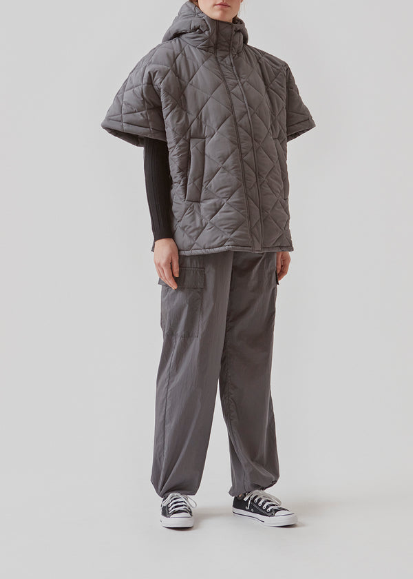 Oversized, quilted poncho with hood in a padded, more responsible material. SophiaMD poncho has deep armholes with press-studs at sides and front. Paspel poc
