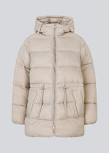 Puffer jacket in beige with an oversized silhouette and adjustable drawstring waist. StellaMD jacket is designed with a high-standing collar, hood, two-way zipper and paspel pockets.