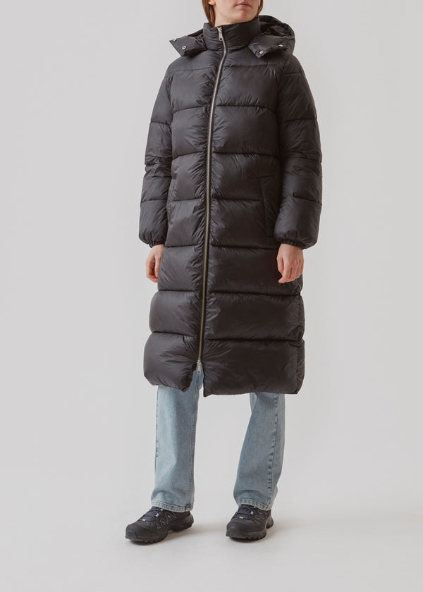 Knee-length coat in black in padded nylon. StellaMD long coat has a relaxed shape with long sleeves, hood and high-standing collar. Two-way zipper, adjustable hood and discreet side pockets.