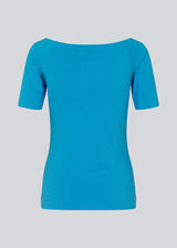 Tansy top in blue has a simple look with a wide neckline at the front and back and narrow sleeves. The top is slim fit without being tight. The model is 174 cm and wears a size S/36