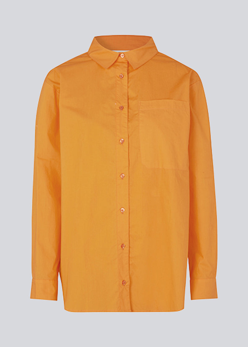 Airy orange shirt in organic cotton poplin. TapirMD shirt has a collar and buttons in front, with an open chest pocket. Dropped shoulders and long sleeves with cuff and button. Embroidered logo in front.