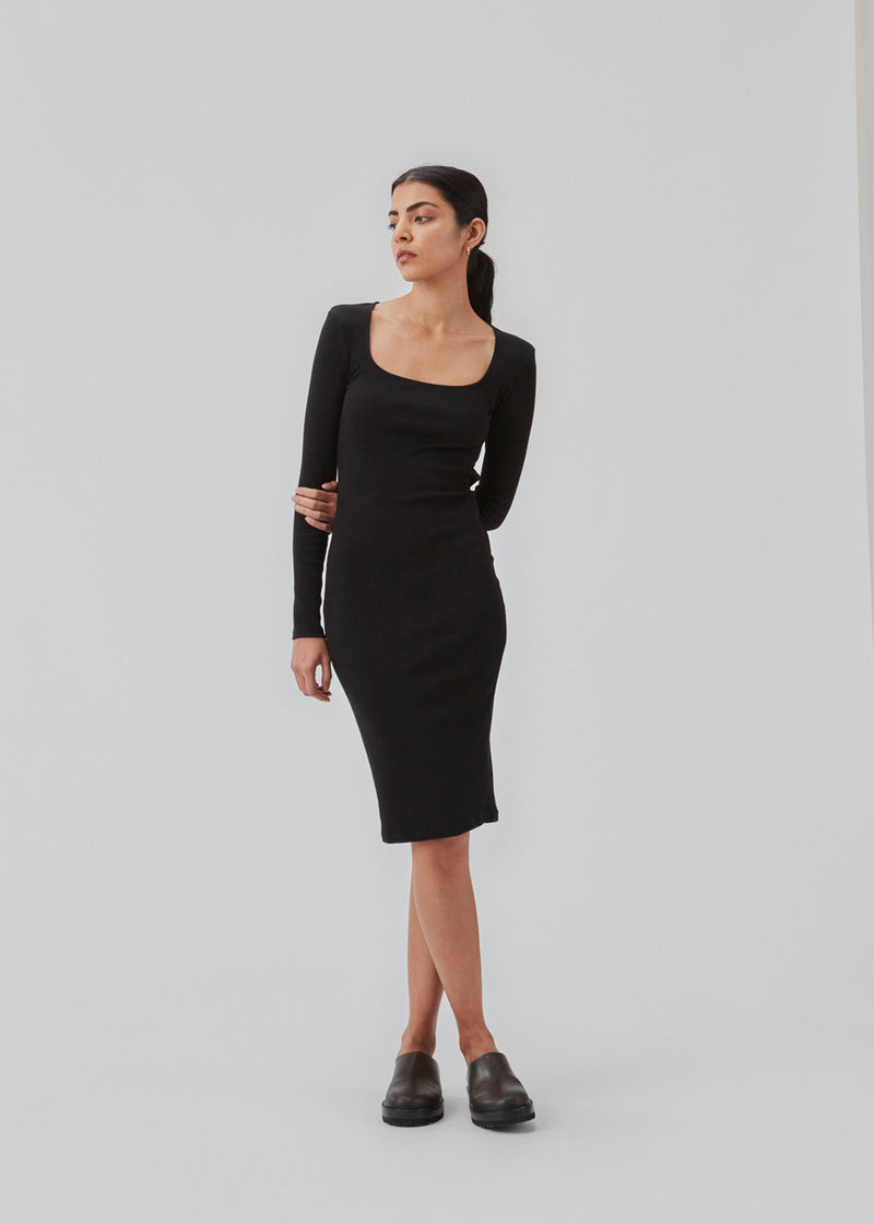 Rib knitted dress in black in a tight fit cotton quality. ToxieMD dress has a square neckline in front and long sleeves. The model is 177 cm and wears a size S/36.