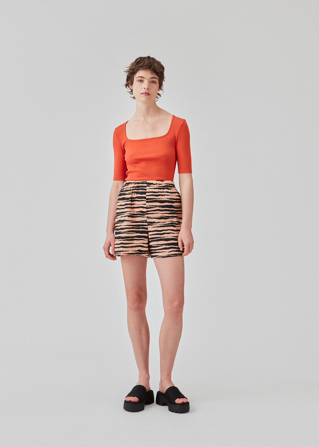 Tight fit top in red in a ribbed cotton jersey with a deep neckline in front and short sleeves cutting just above the elbow. The model is 175 cm and wears a size S/36.