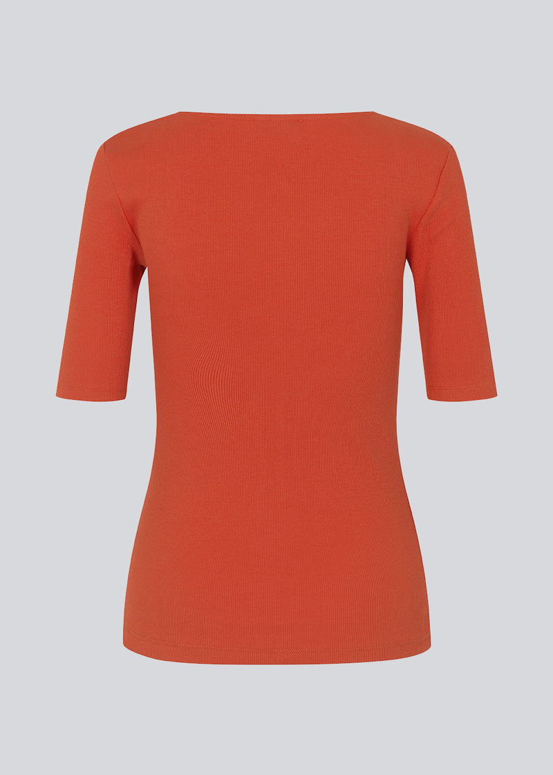 Tight fit top in red in a ribbed cotton jersey with a deep neckline in front and short sleeves cutting just above the elbow. The model is 175 cm and wears a size S/36.