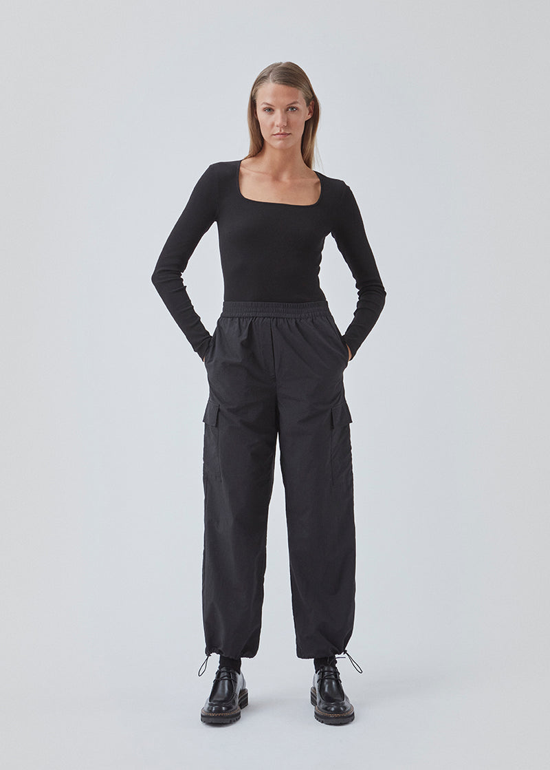 Cargo pants in nylon with elastic waistline and adjustable hems with elastic drawstrings. TrentMD pants have patch pockets on the legs. In black.  This is the same model as our popular pants AmayaMD pants. Just in a thicker material, perfect for fall and winter. 