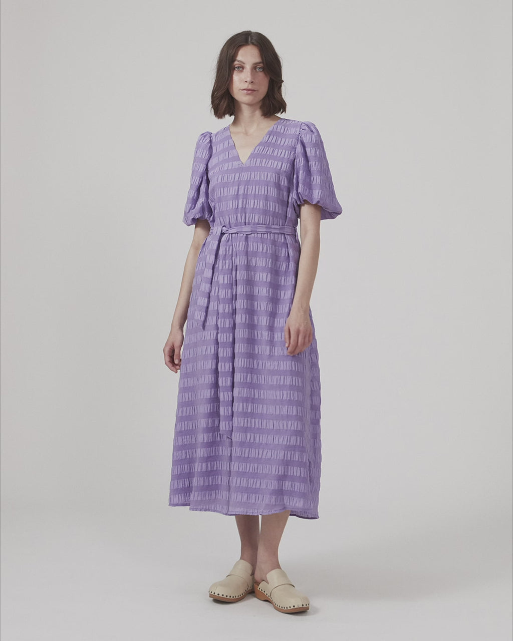 Long dress in structured fabric. CalieMD dress has short puff sleeves, v-shaped neckline, and a tie-belt at the waist.  The model is 177 cm and wears a size S/36.